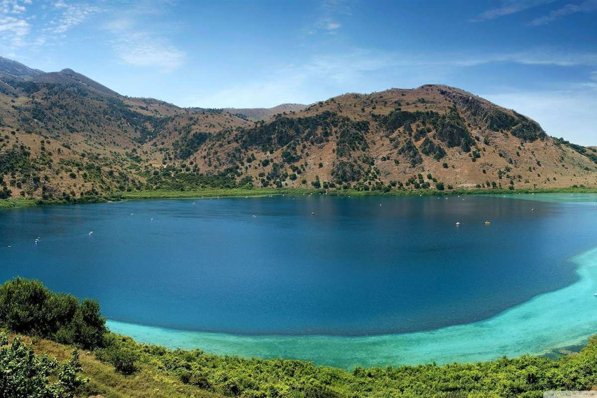 Classical Greece tour with the islands: a deep blue mountain lake with turquoise shallows along the shore, surrounded by green hills on the island of Crete