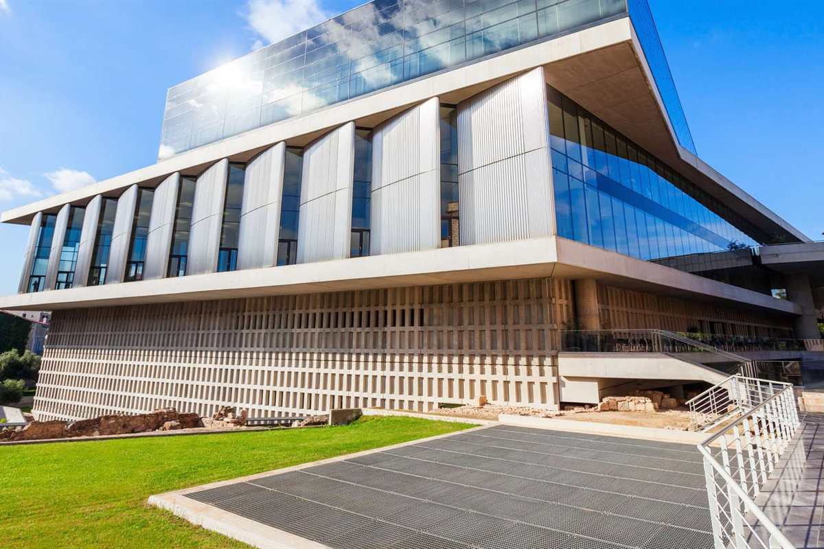Acropolis guided tour with Acropolis Museum: the modern Acropolis Museum building with its glass top floor and pale columns under a clear blue sky in Athens