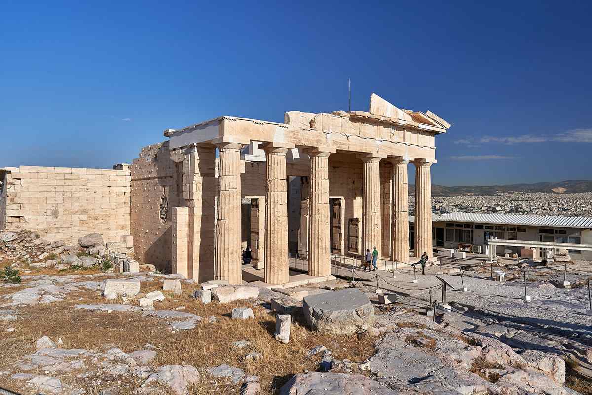 Acropolis ticket with audio guide: the Doric columns of the Propylaea gateway on the Acropolis rock under a deep blue sky, with Athens spread out behind