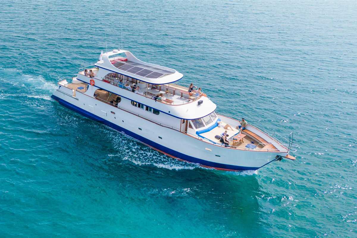 Larnaca snorkeling cruise: a white and navy cruise boat with passengers on its sun decks and a red lifebelt sails across clear turquoise water and leaves a white wake behind the hull